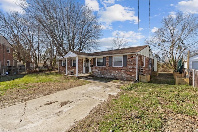 view of front of home featuring a front lawn, fence, brick siding, and driveway