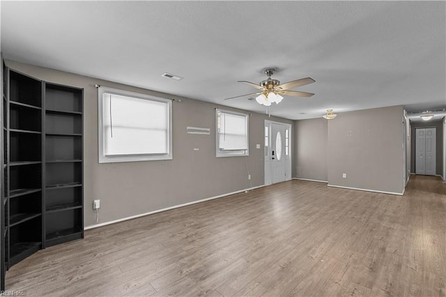 unfurnished living room featuring visible vents, baseboards, ceiling fan, and wood finished floors