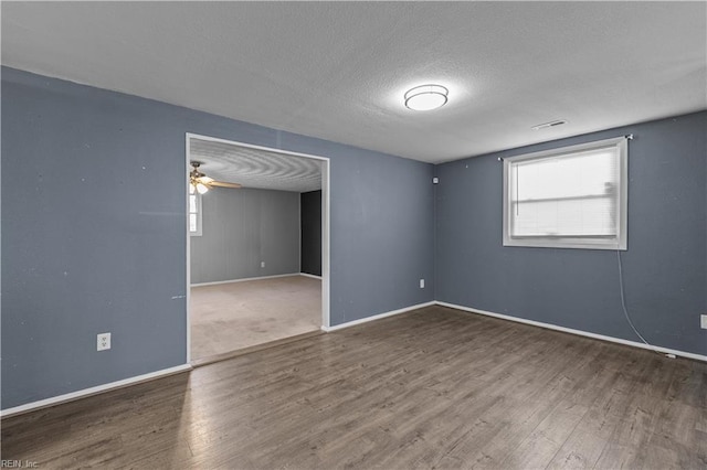 spare room with baseboards, a textured ceiling, and wood finished floors