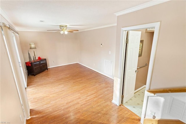 spare room with light wood finished floors, visible vents, a ceiling fan, and ornamental molding