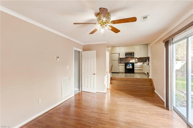 interior space featuring light wood-style flooring, baseboards, visible vents, and ornamental molding