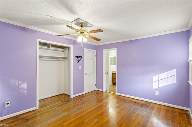 unfurnished bedroom featuring baseboards, hardwood / wood-style floors, and crown molding