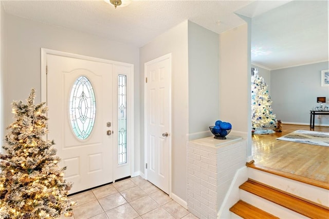 foyer entrance with light tile patterned floors, baseboards, and a textured ceiling