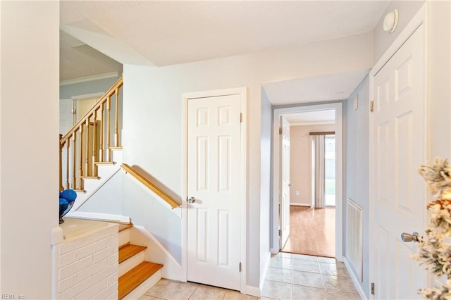 staircase with tile patterned floors, crown molding, and baseboards