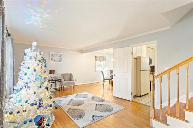 living area featuring light wood finished floors, stairs, baseboards, and ornamental molding