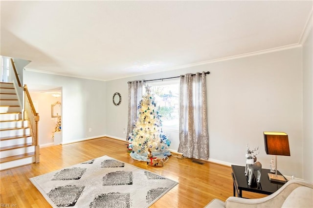 living area with ornamental molding, stairs, baseboards, and wood finished floors