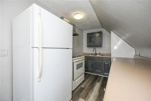 kitchen with white appliances, dark wood finished floors, a sink, vaulted ceiling, and a textured ceiling