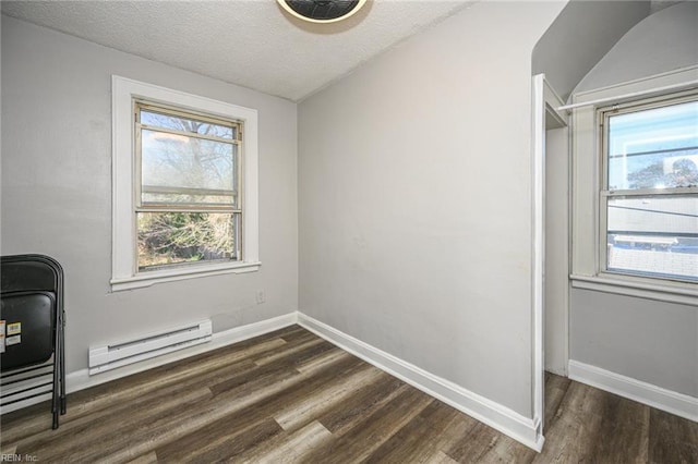 interior space with a baseboard heating unit, dark wood-style floors, baseboards, and a textured ceiling