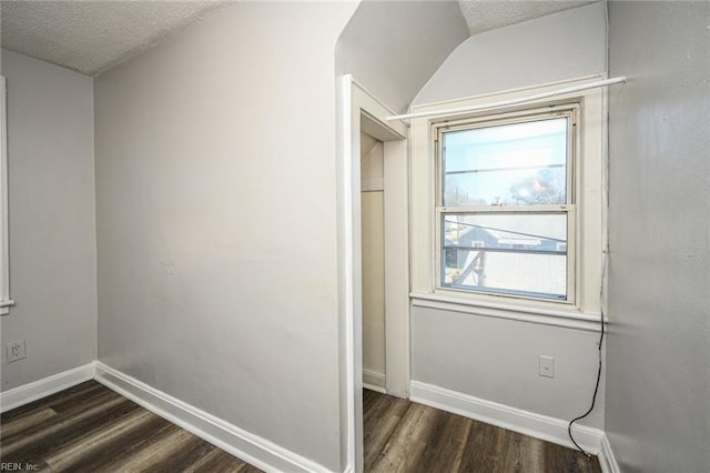 interior space featuring vaulted ceiling, baseboards, dark wood-style flooring, and a textured ceiling