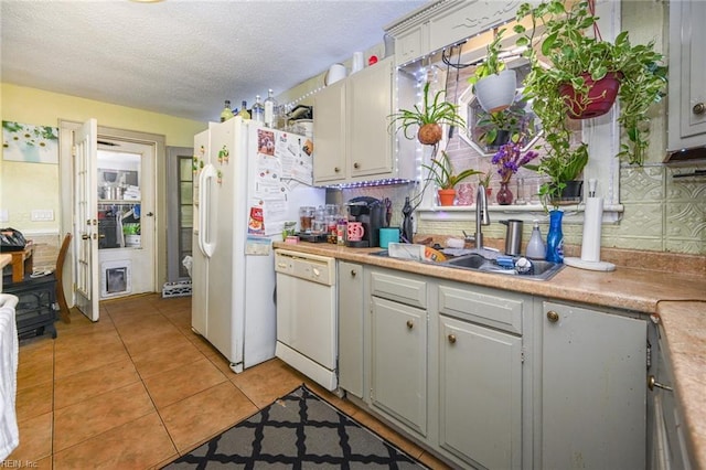 kitchen featuring white appliances, light tile patterned floors, a sink, light countertops, and backsplash