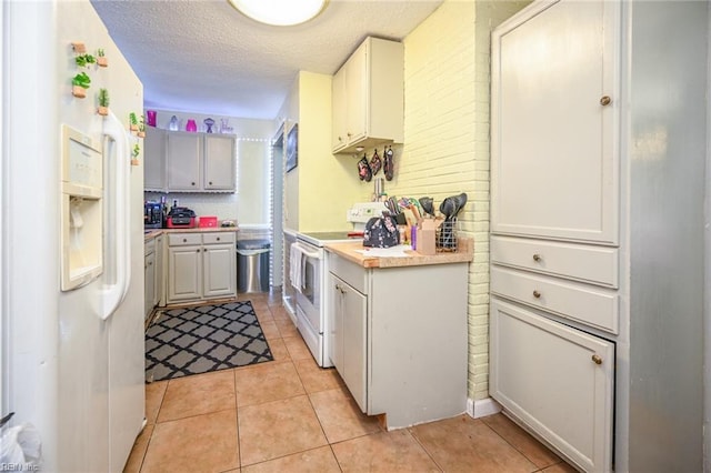 kitchen featuring light tile patterned flooring, white appliances, a textured ceiling, and light countertops