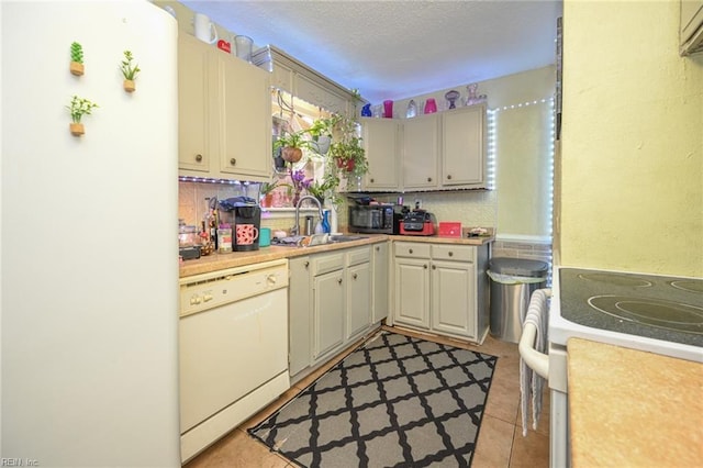 kitchen featuring a textured ceiling, white appliances, light countertops, and a sink