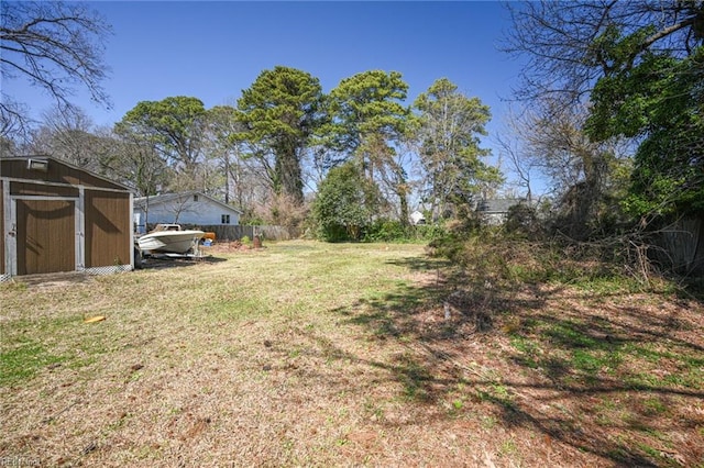 view of yard featuring an outbuilding, a storage shed, and fence