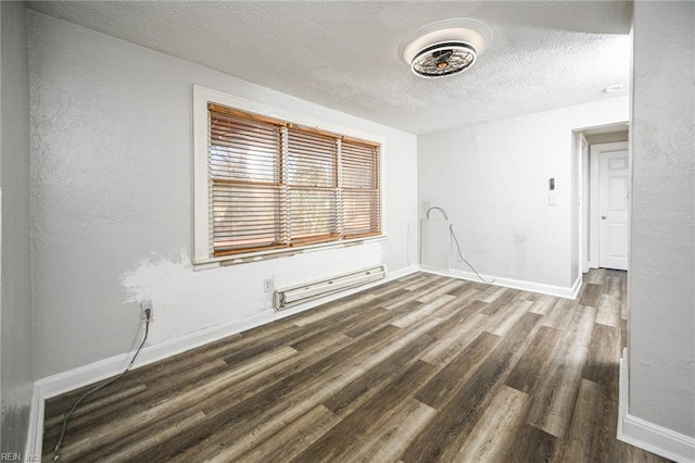 empty room with a baseboard heating unit, baseboards, wood finished floors, a textured wall, and a textured ceiling