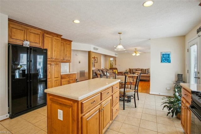 kitchen featuring brown cabinets, black fridge with ice dispenser, light tile patterned flooring, and light countertops