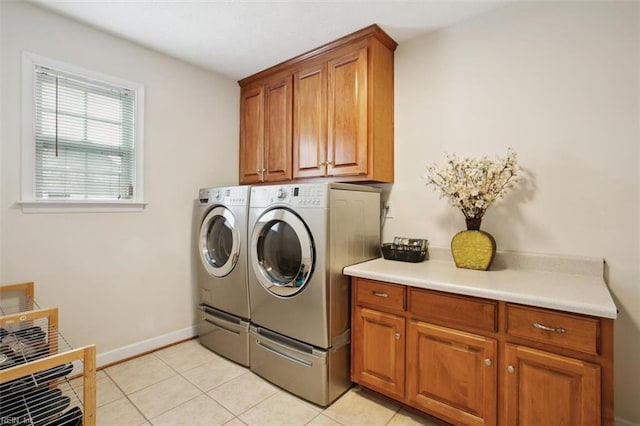 laundry area with light tile patterned floors, washing machine and dryer, cabinet space, and baseboards