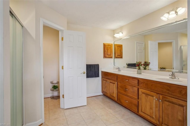 full bath with a sink, baseboards, double vanity, and tile patterned floors