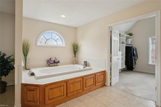 bathroom with lofted ceiling, recessed lighting, tile patterned flooring, a walk in closet, and a garden tub