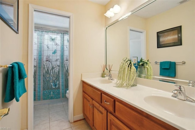 bathroom with tile patterned floors, toilet, double vanity, and a sink