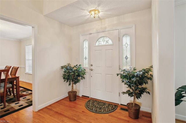 foyer entrance with visible vents, a healthy amount of sunlight, baseboards, and light wood finished floors