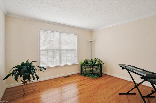 living area featuring visible vents, a textured ceiling, wood finished floors, crown molding, and baseboards