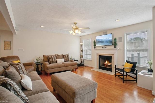 living area with a premium fireplace, recessed lighting, light wood finished floors, and a textured ceiling