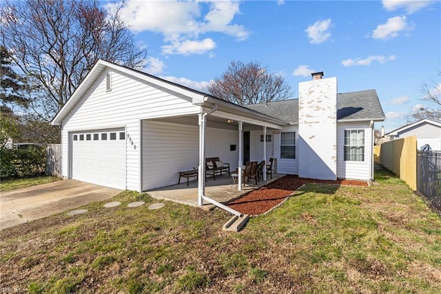 exterior space featuring a lawn, fence, concrete driveway, an attached garage, and a chimney