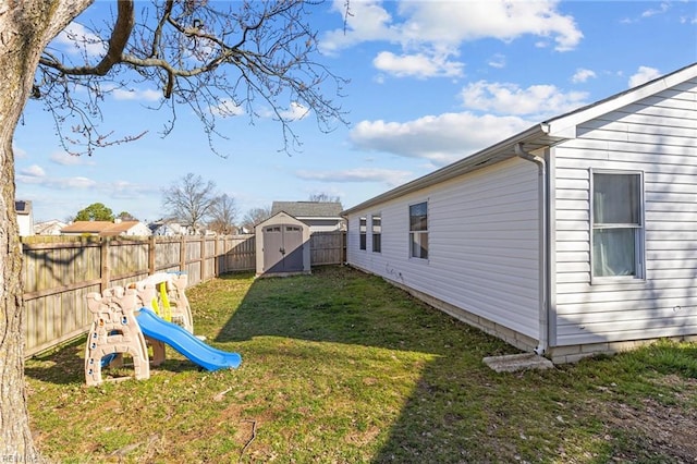 view of yard with a storage unit, an outdoor structure, a fenced backyard, and a playground