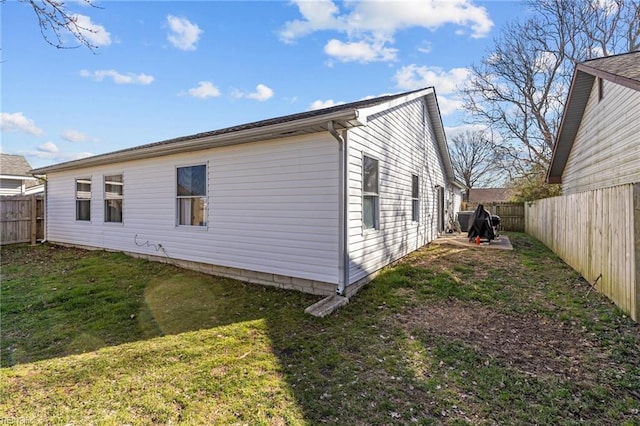 view of side of property featuring a lawn and a fenced backyard