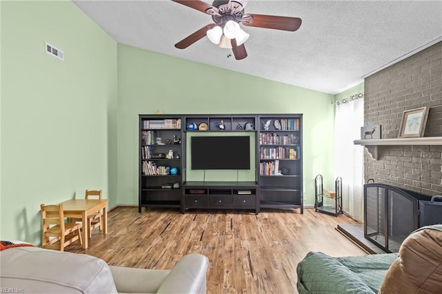 living area featuring lofted ceiling, wood finished floors, visible vents, and a textured ceiling