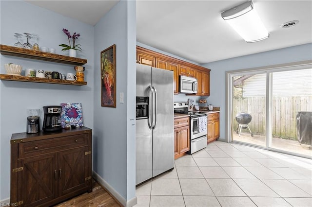 kitchen with visible vents, baseboards, light tile patterned floors, brown cabinets, and stainless steel appliances