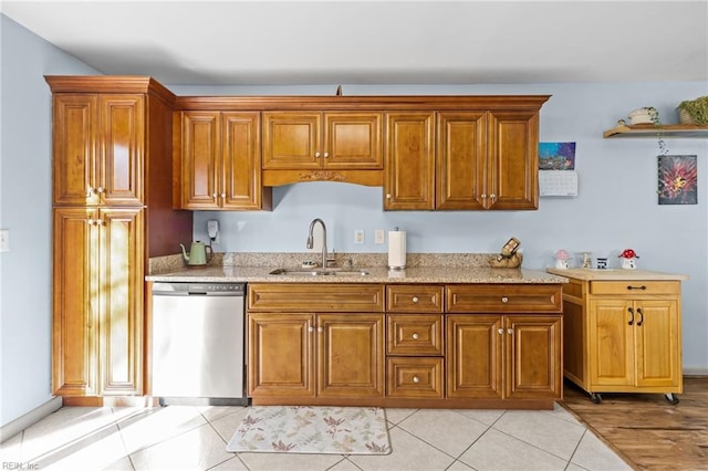 kitchen with light tile patterned floors, brown cabinets, dishwasher, and a sink