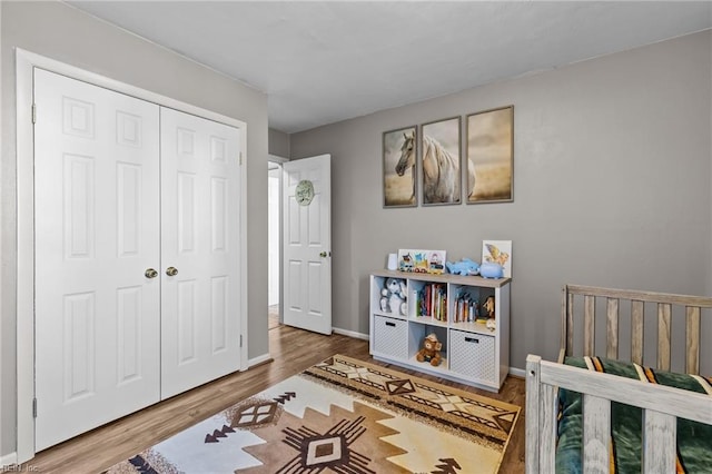 bedroom with wood finished floors, a closet, and baseboards