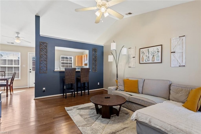 living room with visible vents, baseboards, vaulted ceiling, hardwood / wood-style floors, and a ceiling fan