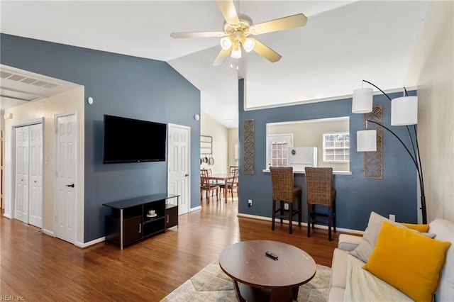 living area featuring a ceiling fan, lofted ceiling, wood finished floors, and baseboards