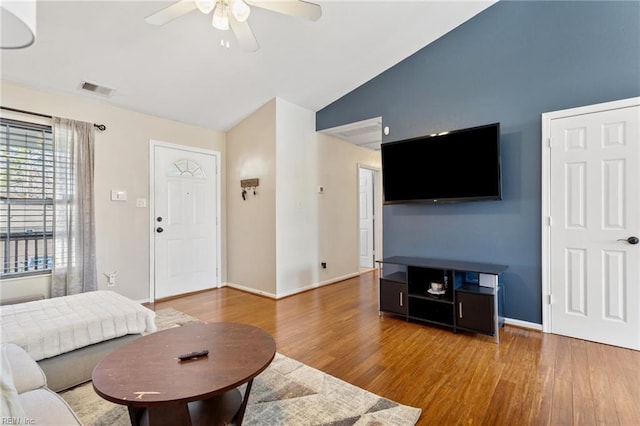 living area featuring wood finished floors, baseboards, visible vents, ceiling fan, and vaulted ceiling