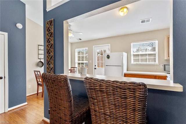 dining area featuring visible vents, baseboards, light wood-style floors, and a ceiling fan