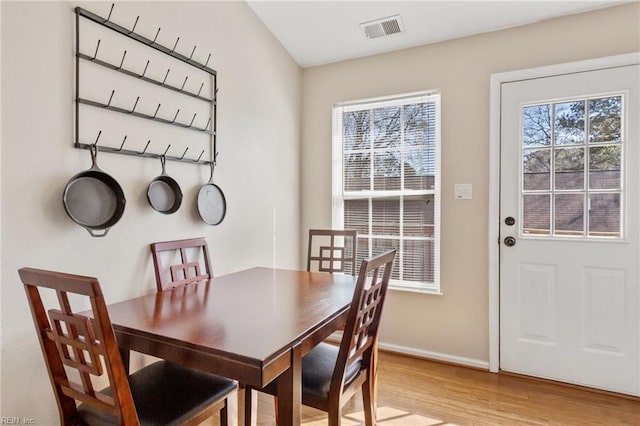 dining space featuring visible vents, light wood-style flooring, and baseboards