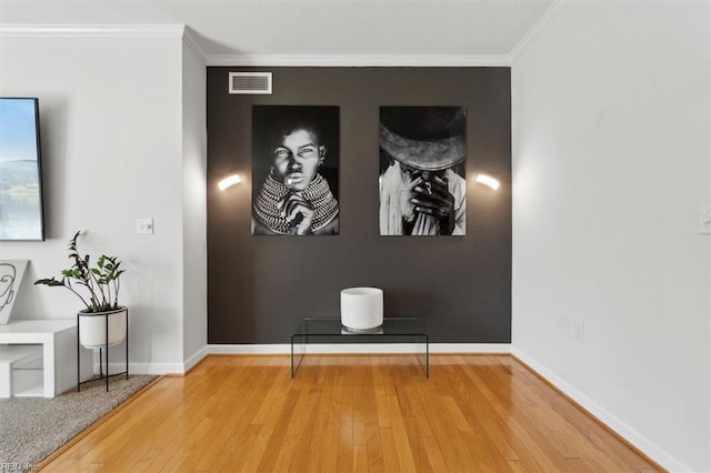 interior space featuring baseboards, visible vents, wood-type flooring, and ornamental molding