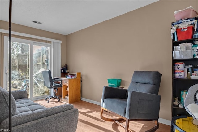 home office with a wealth of natural light, visible vents, baseboards, and wood finished floors