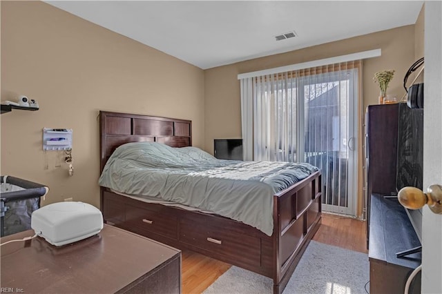 bedroom with visible vents, light wood-style flooring, and access to outside