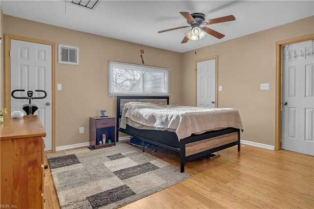 bedroom with ceiling fan, light wood-style floors, visible vents, and baseboards