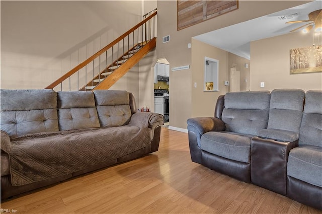 living room with light wood finished floors, visible vents, stairs, and baseboards