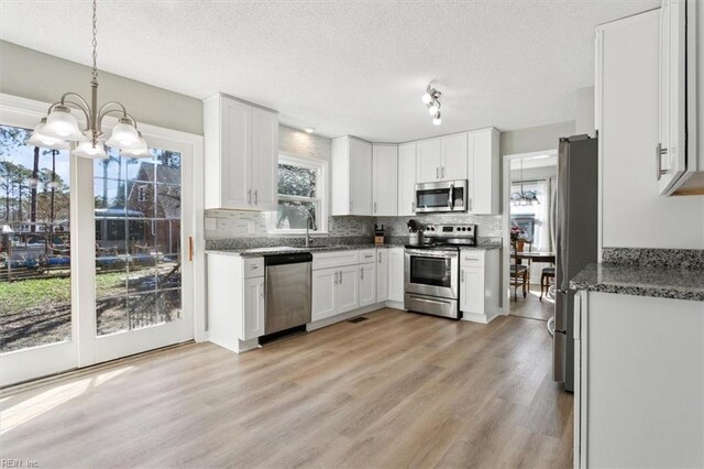 kitchen with decorative backsplash, white cabinets, stainless steel appliances, and light wood-type flooring