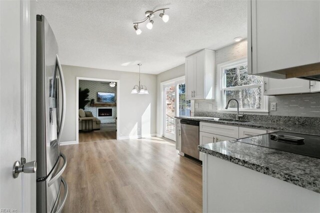 kitchen featuring a fireplace, tasteful backsplash, appliances with stainless steel finishes, and a sink