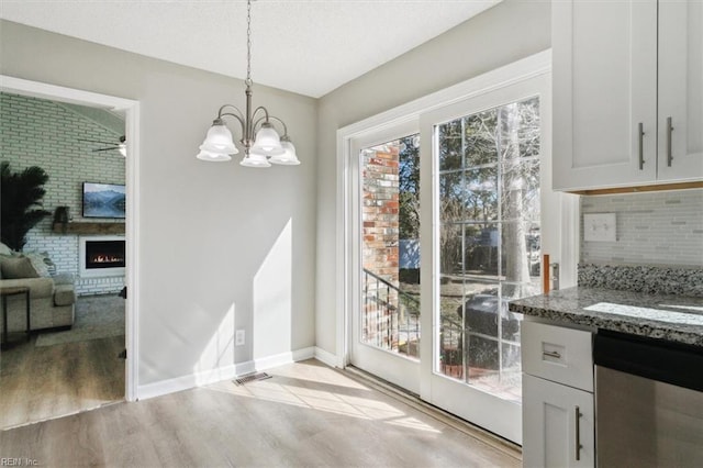 dining space with light wood-type flooring, baseboards, an inviting chandelier, and a fireplace