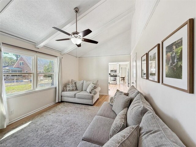 living room with wood finished floors, baseboards, lofted ceiling with beams, ceiling fan, and a textured ceiling