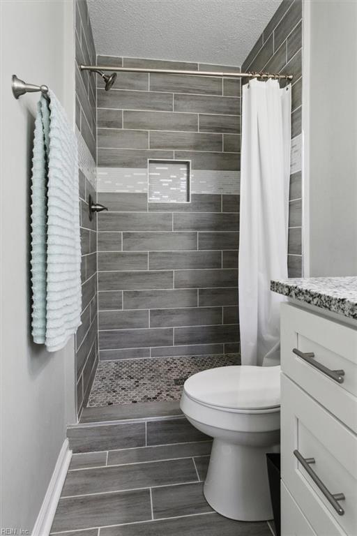 bathroom featuring vanity, a shower stall, toilet, and a textured ceiling