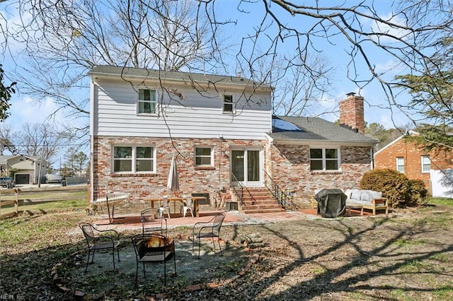 rear view of house with entry steps, fence, brick siding, a chimney, and a patio area