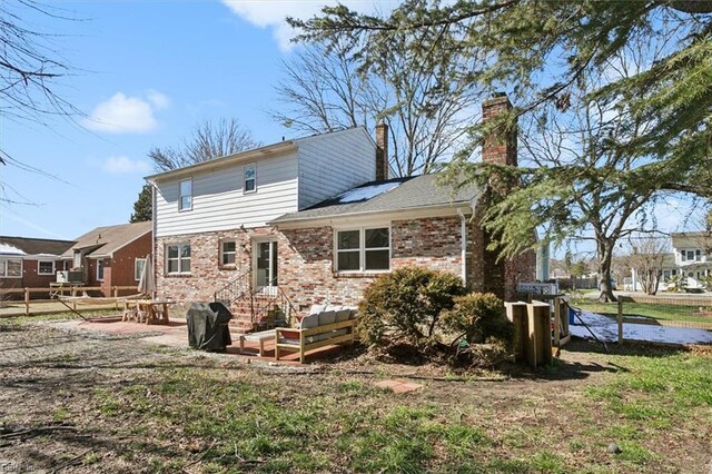 rear view of property featuring an outdoor living space, brick siding, a chimney, and a patio area